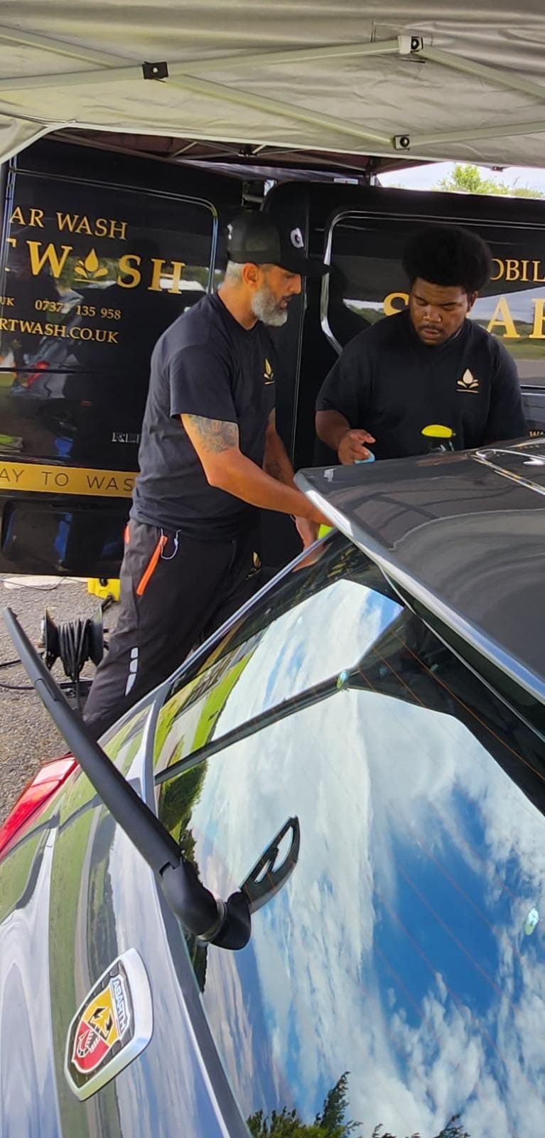 Two SmartWash team members polishing a car